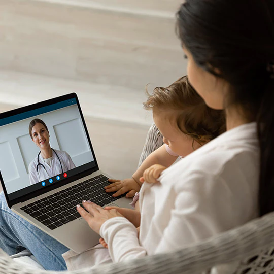 Woman and child having a telemedicine appointment with a doctor on a laptop.